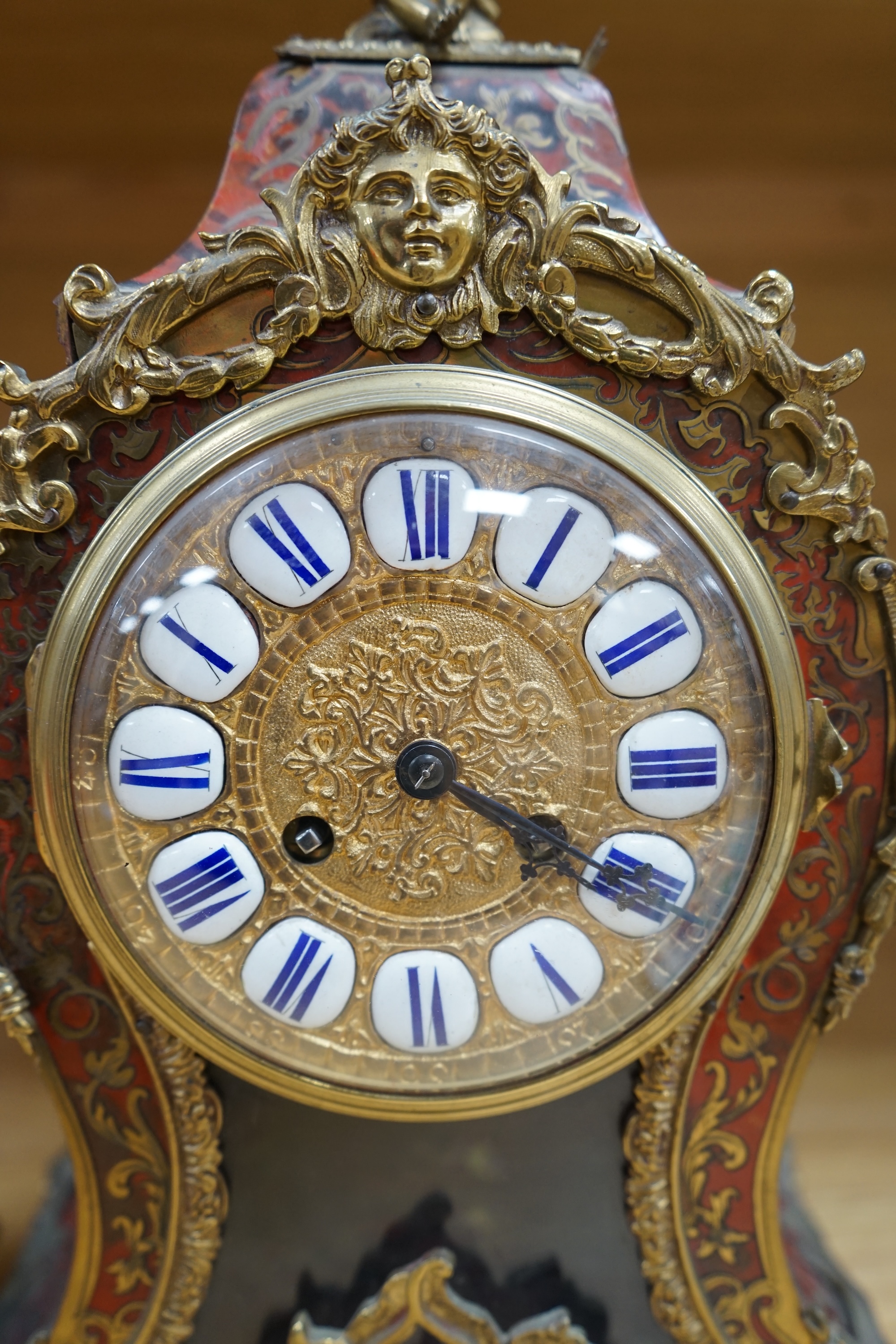 A French scarlet Boulle clock, and original bracket, the waisted case with glass front enclosing boulle interior and sunburst pendulum, c. 1860, clock 42cm high. Condition - fair, untested